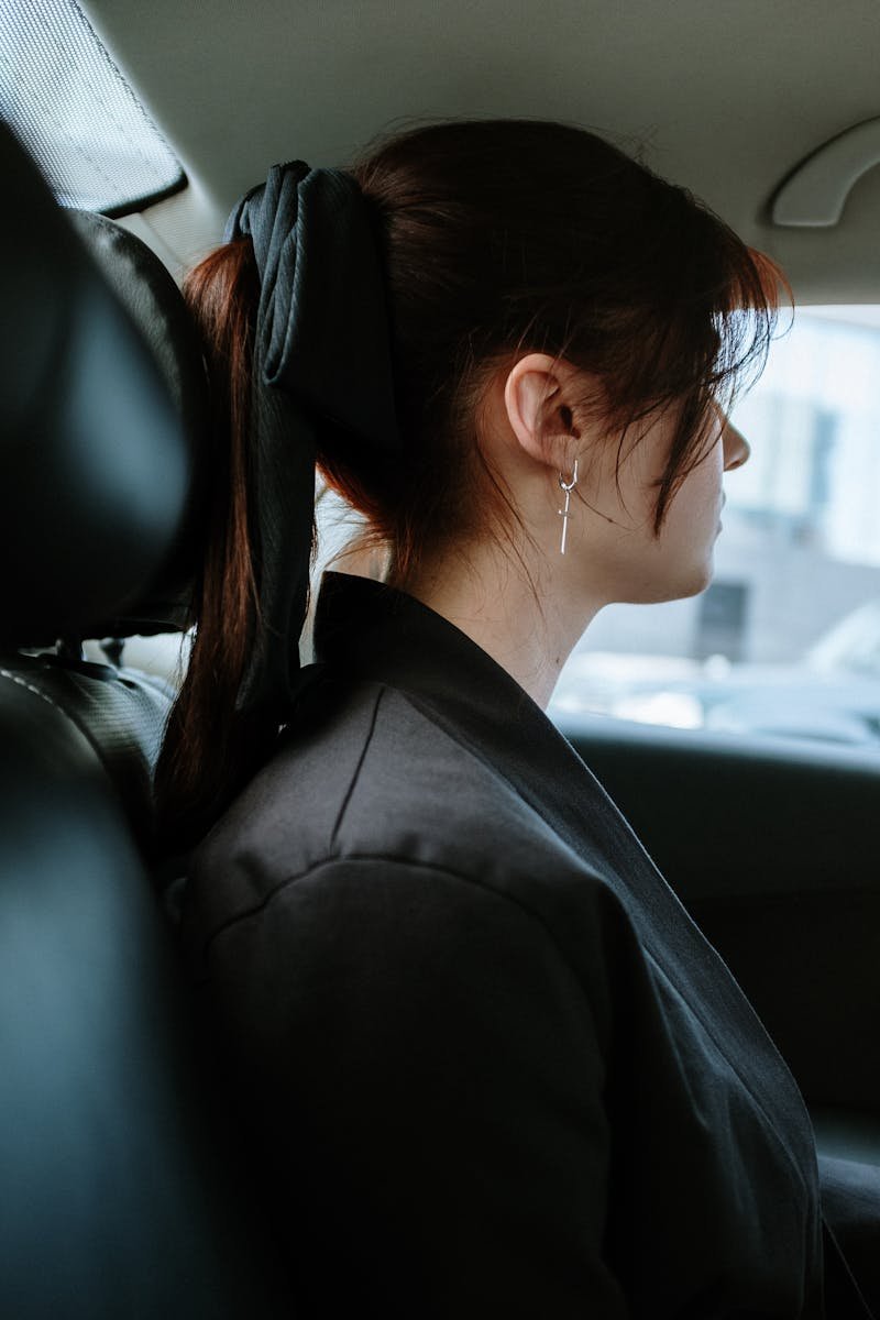 Profile of a woman with earrings in a car, showcasing modern urban transport.